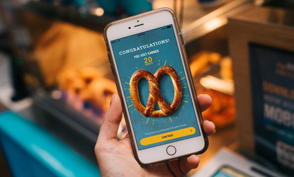 Holding smart phone with Pretzel Perks app open at Auntie Annes.